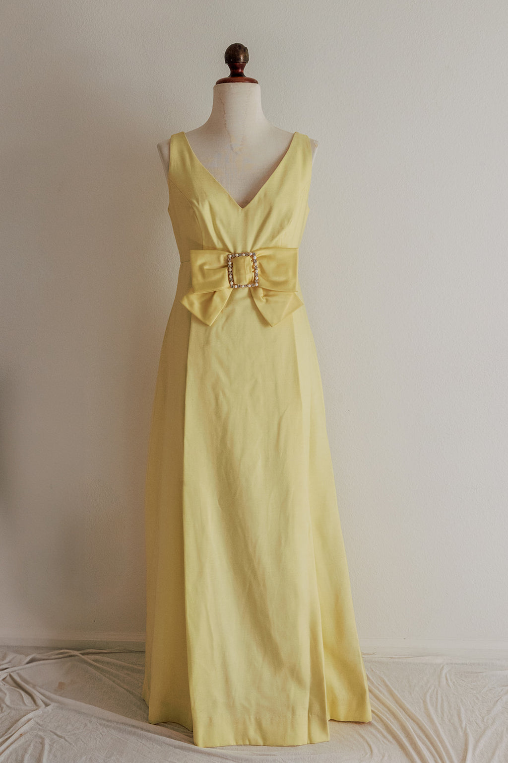 Yellow evening gown on a mannequin against a plain background